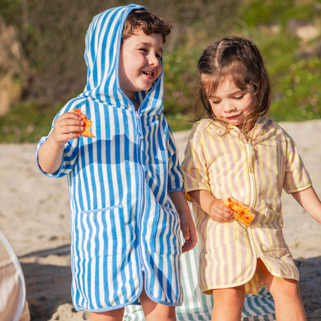 a boy and girl wearing ponchos eating pizza