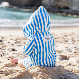 baby boy wearing blue and white striped poncho playing in the sand