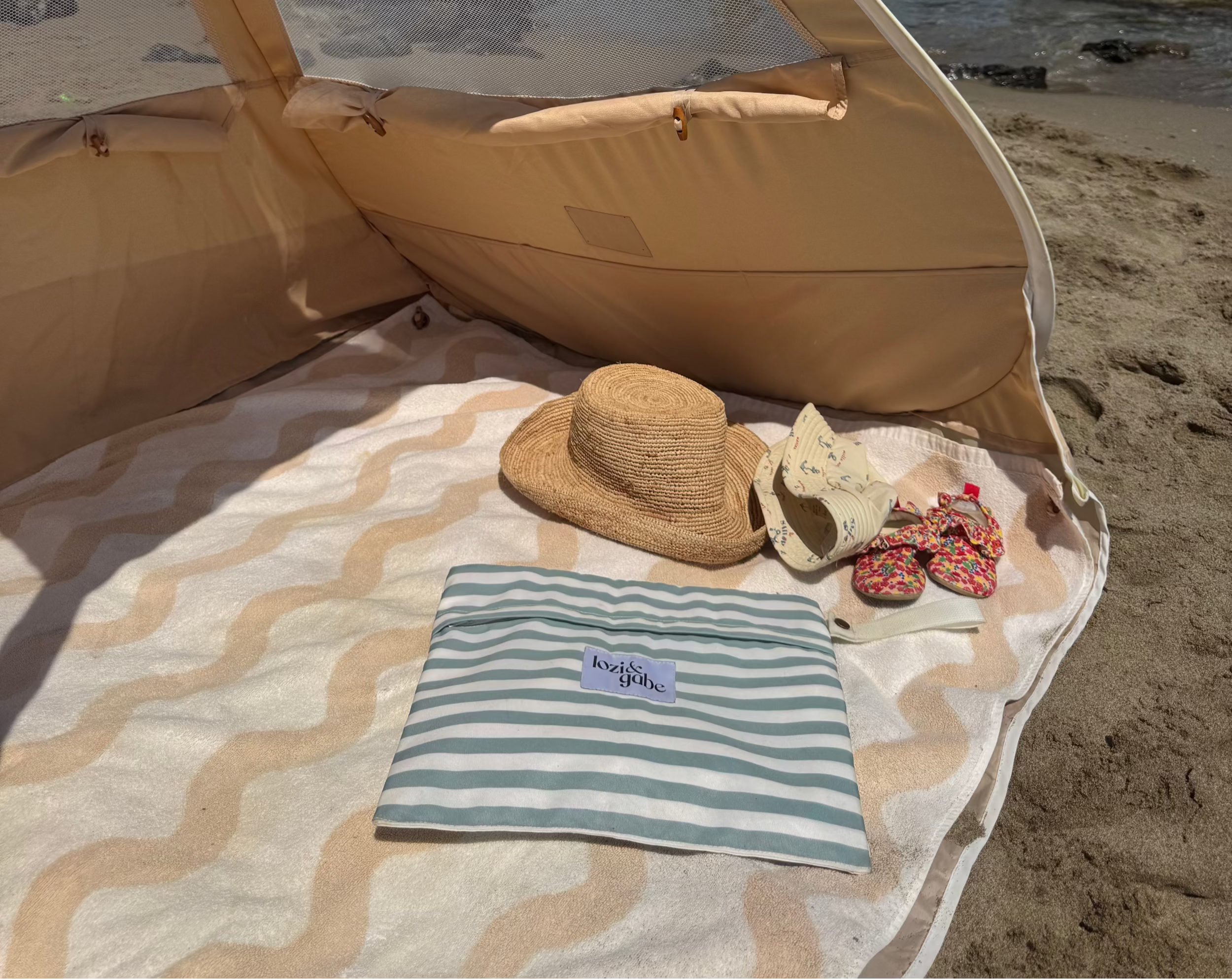 Beach tent with beach accessories on a sandy shore with ocean view